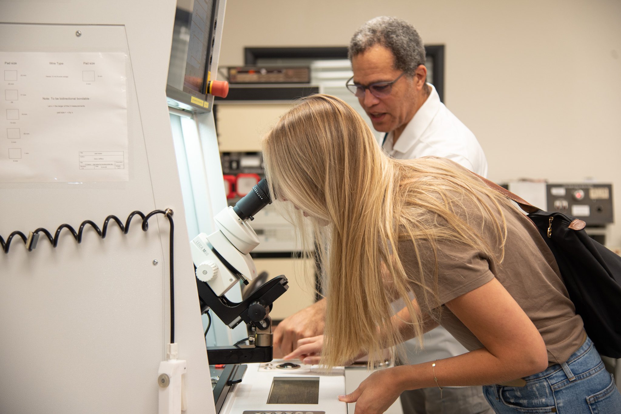 SNT_3064 A woman looking through a microscope with a man standing behind her