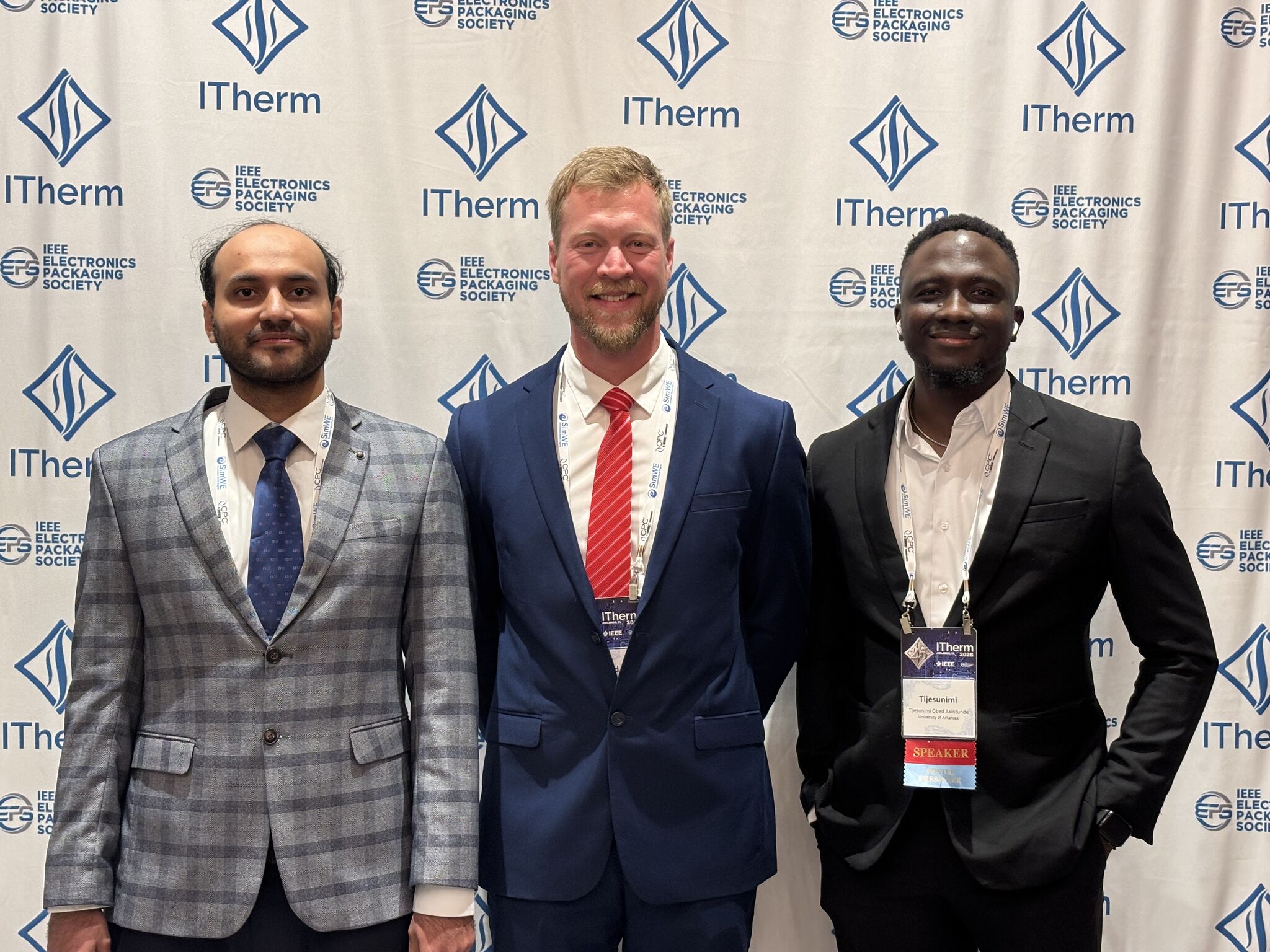 Three researchers stand in front of an IEEE ITherm 2026 conference backdrop after presenting research on thermal management and electronics cooling.